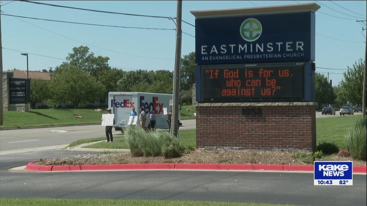 Community members holding signs demanding accountability outside Eastminster Presbyterian Church